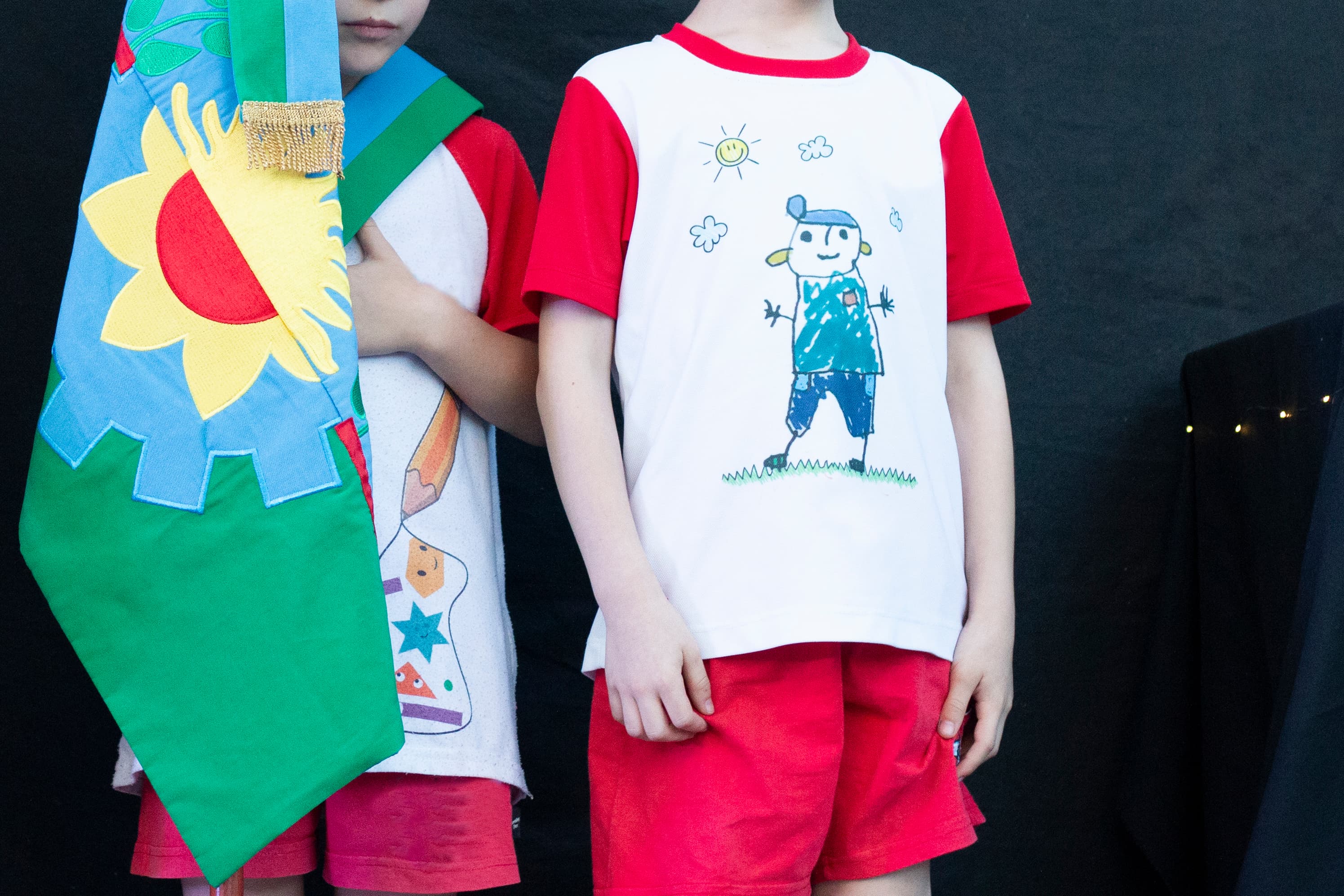 Alumnos en un acto escolar con estandarte y remeras pintadas