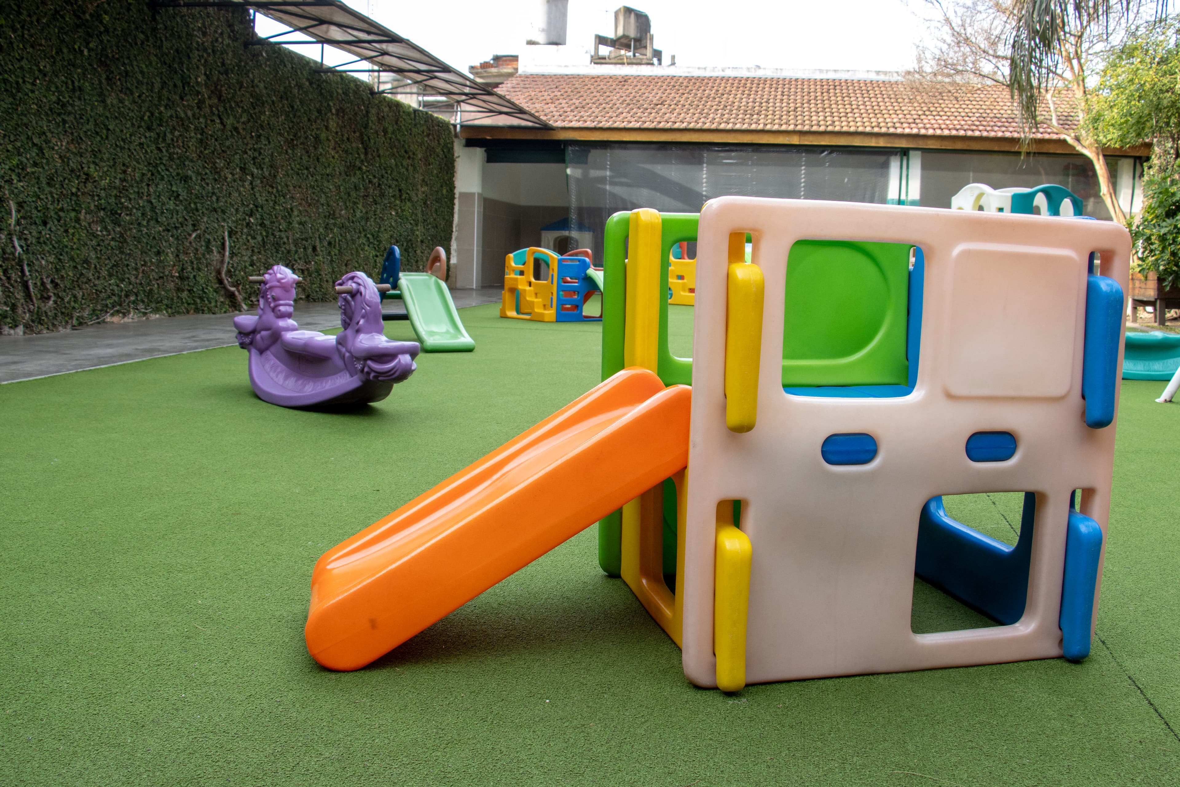 Patio de juegos del jardín con tobogán y césped sintético